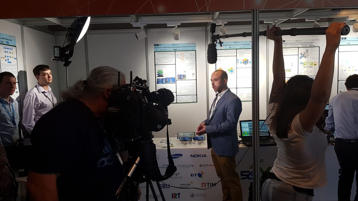 A camera crew filming a demo in a lab full of project posters