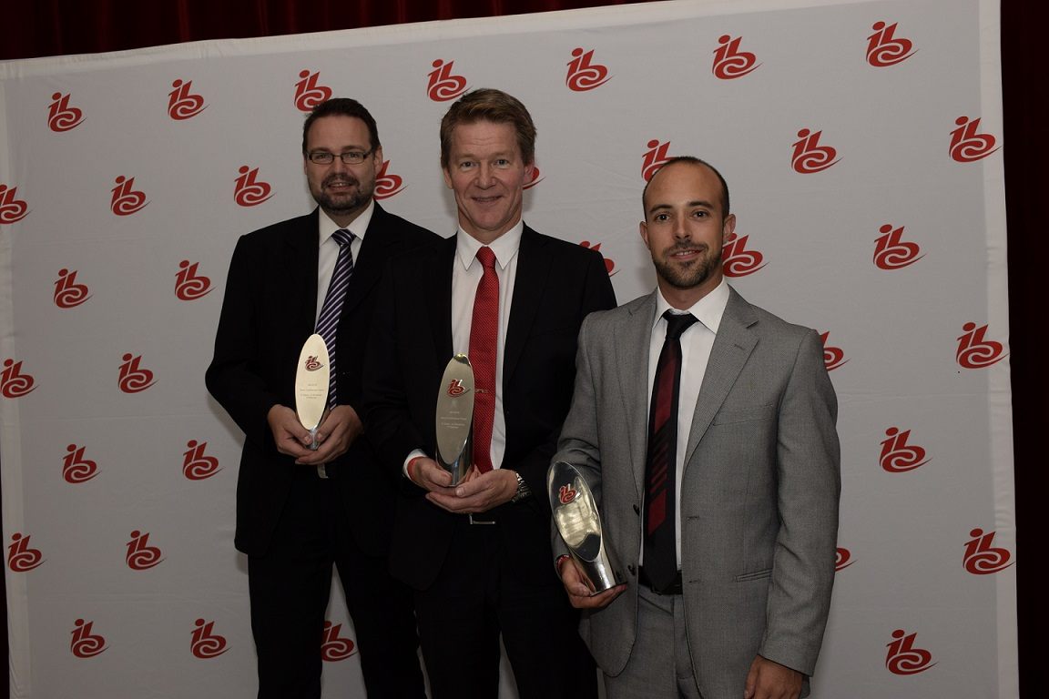 Three people holding IBC award trophies in front of an IBC backdrop