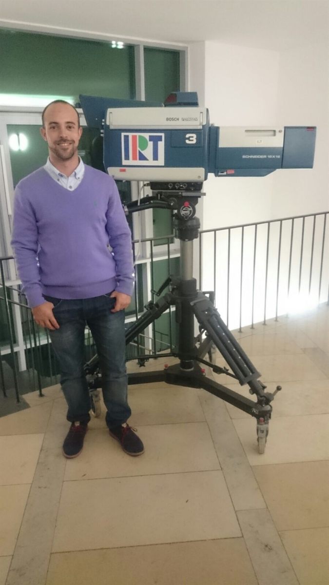 Jordi-Joan standing next to a studio TV camera with the IRT logo