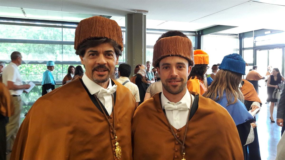 Two graduates in doctoral robes and caps at a ceremony